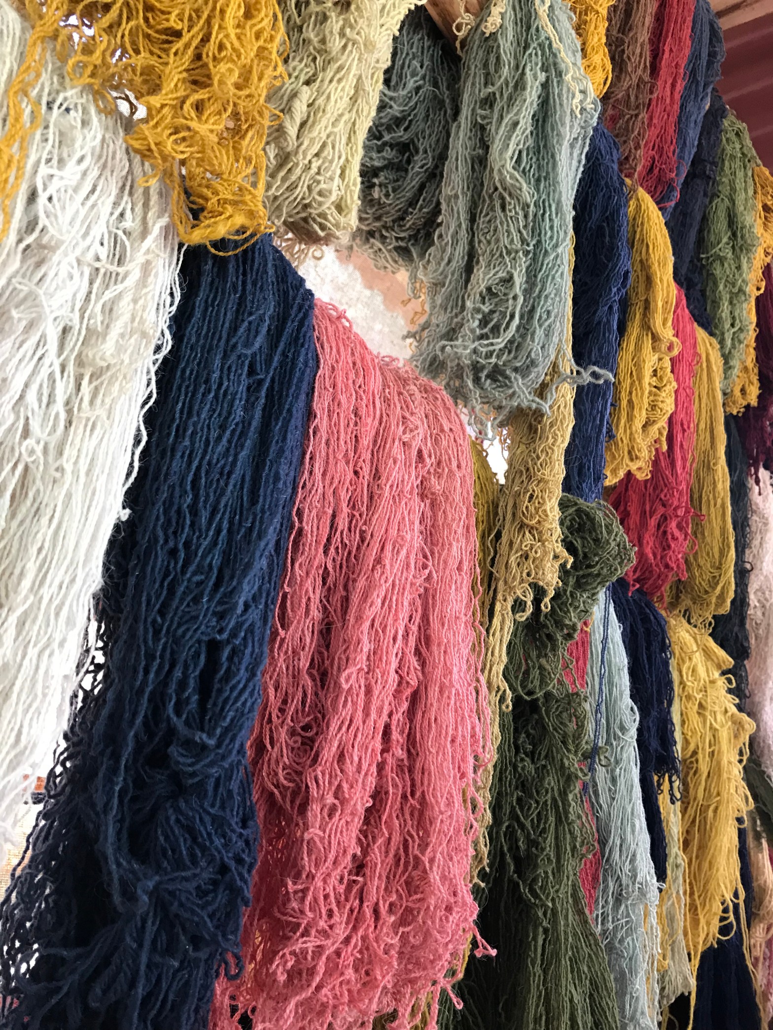 Image Description: Multi-colored yarn hanging from the ceiling.